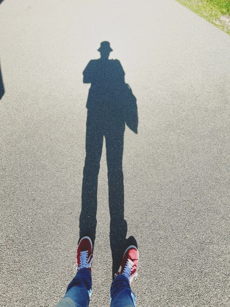 the photographer's long shadow with a hat and red shoes
