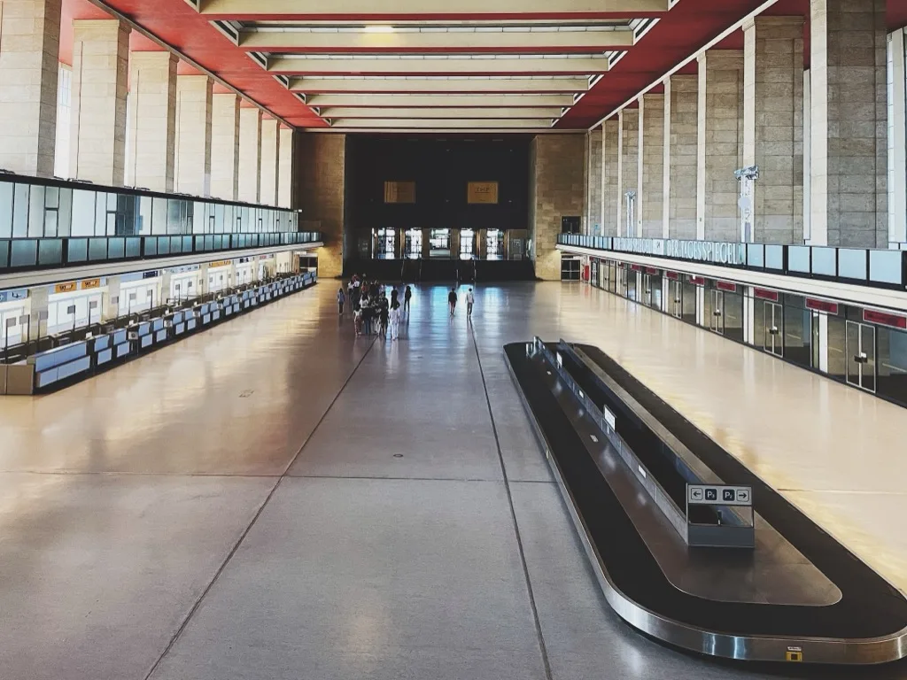 the vast empty arrivals hall, red ceiling beams